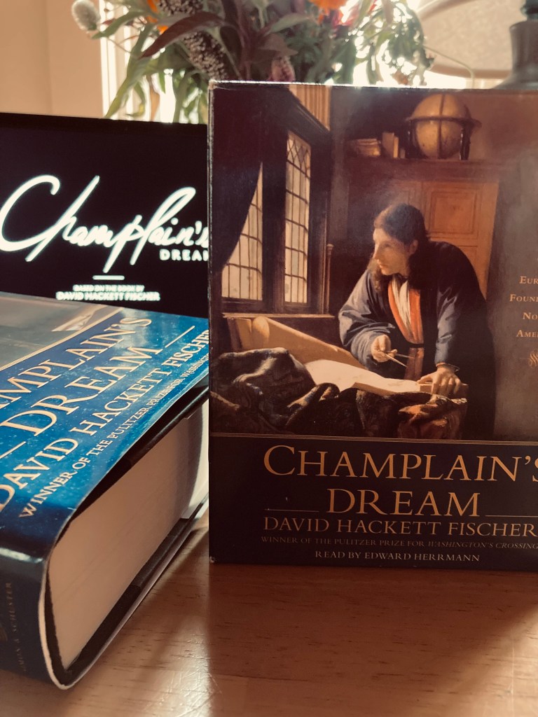 A book, audiobook, and laptop on a table.